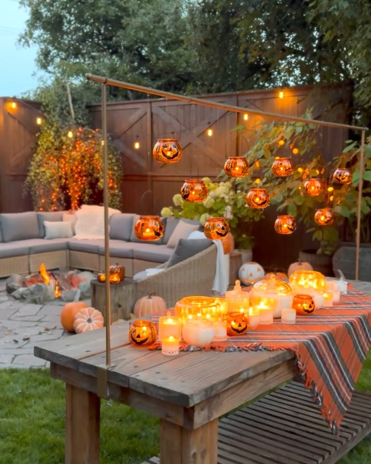 Glowing pumpkin lanterns and candles decorate a cozy outdoor Halloween dining area