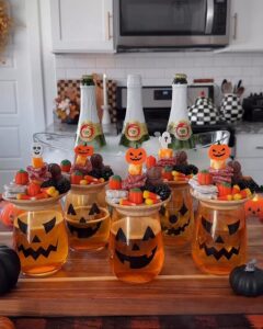 cheap halloween party ideas with pumpkin-face drink jars, candy, orange punch, and spooky dessert displays