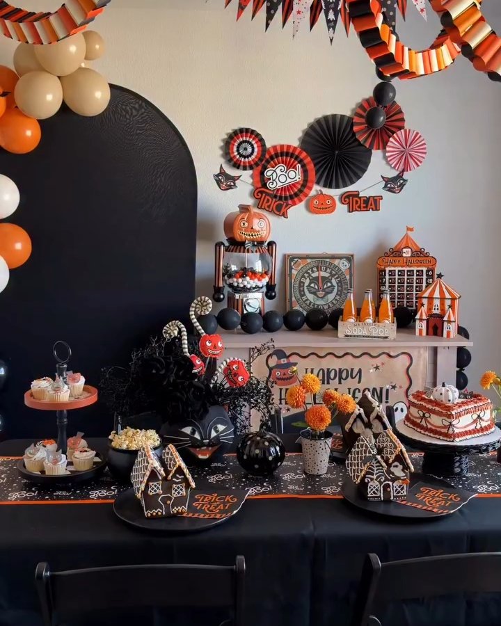 Black and orange paper fan backdrop with Halloween treats for an affordable party setup