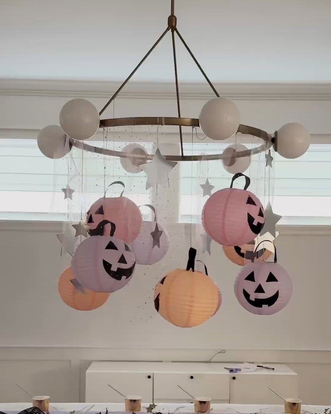 DIY Halloween party decor with pastel pumpkin lanterns and hanging silver stars