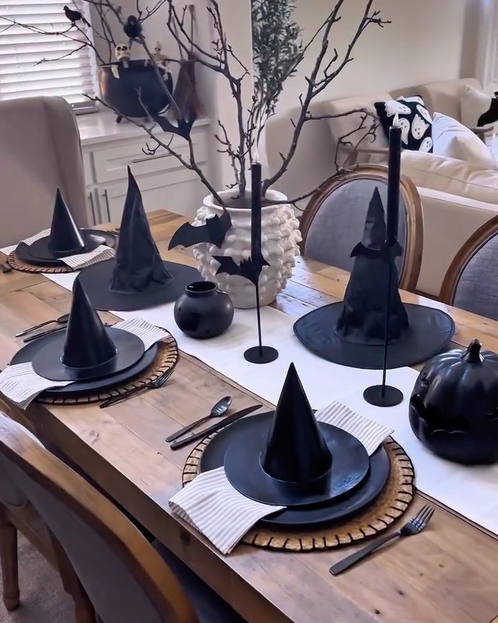 Witch hats, black pumpkins, paper bats, and branch decor create cheap halloween party ideas for a stylish table