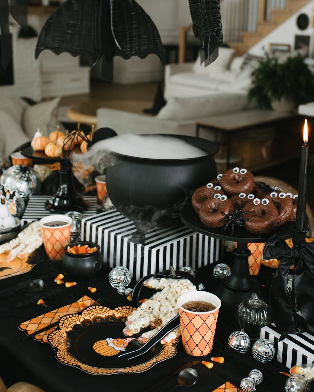 Black bat decorations, striped boxes, spooky treats, and orange tableware create an affordable Halloween buffet