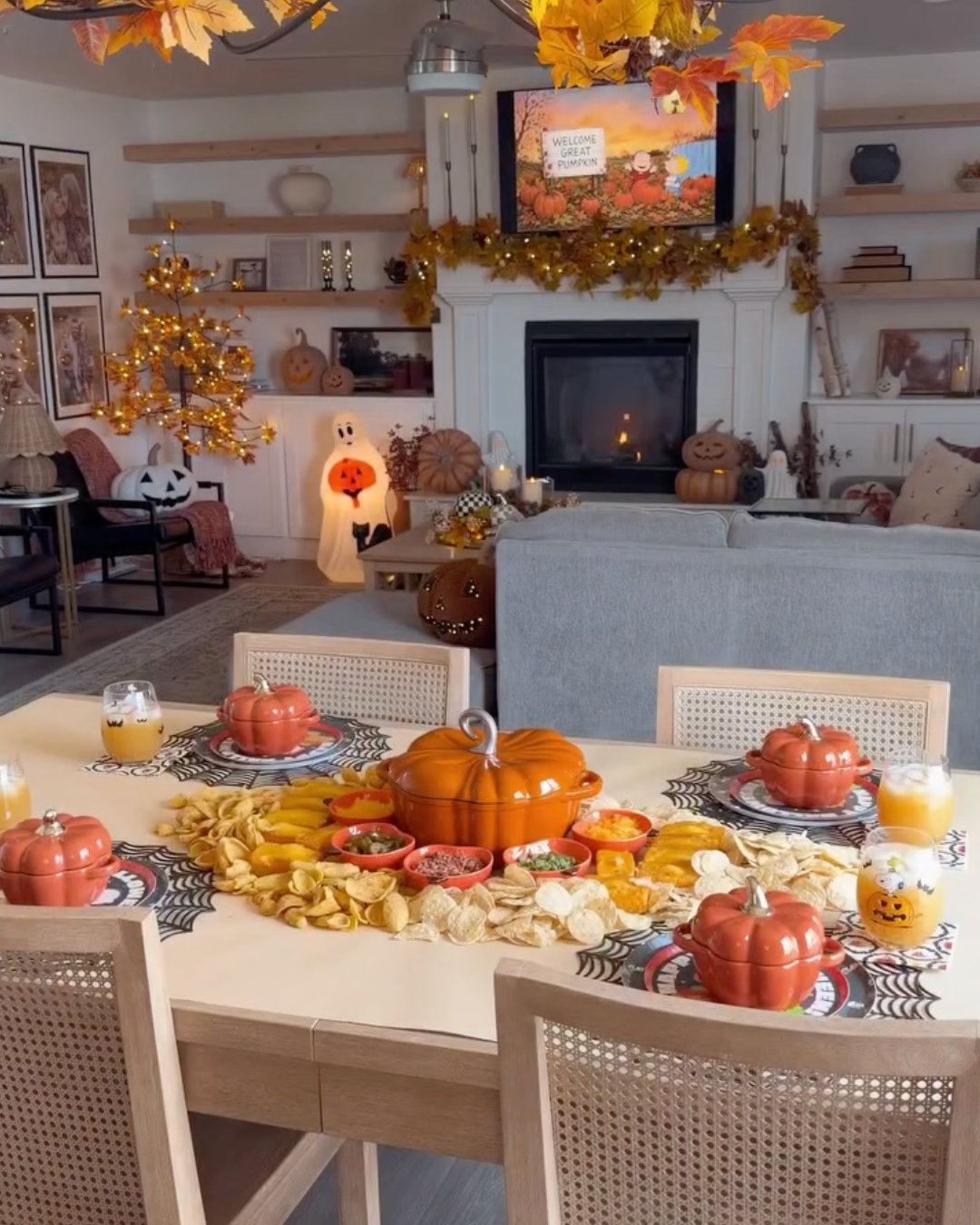 Budget-friendly Halloween dining table with pumpkin dishes, snack spread, glowing lights, and autumn leaf decor