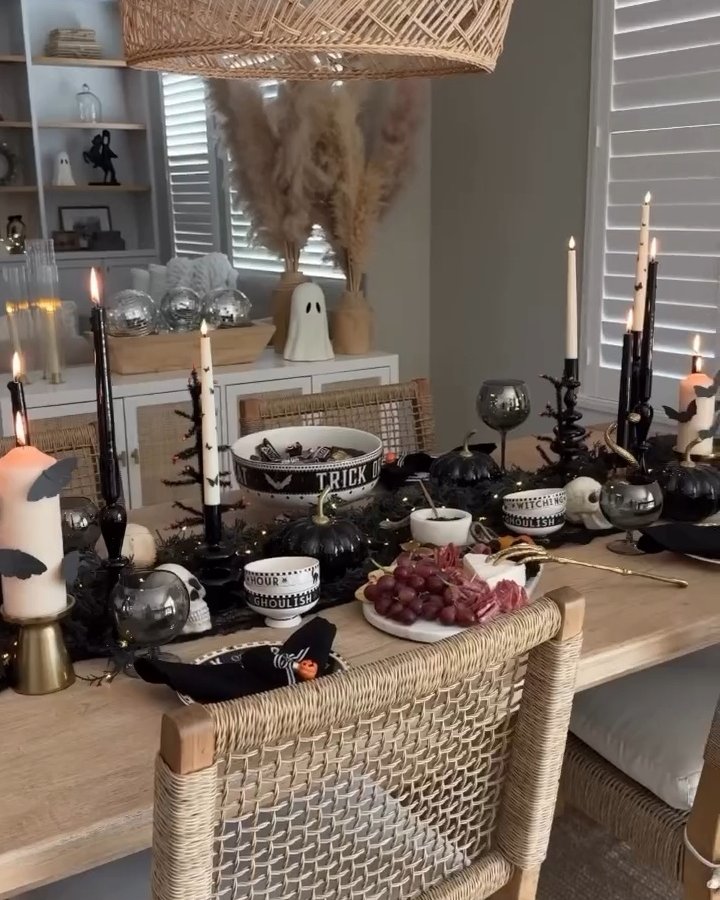 Black candlelit Halloween table with ghost decor, dark pumpkins, themed bowls, and simple party snacks