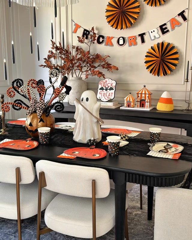 Budget-friendly Halloween dining room with orange paper fans, ghost centerpiece, candy accents, and festive tableware