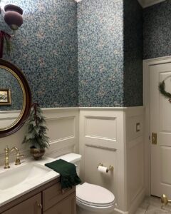 Botanical wallpaper, frosted mini tree, and green accents showcase christmas bathroom decor ideas