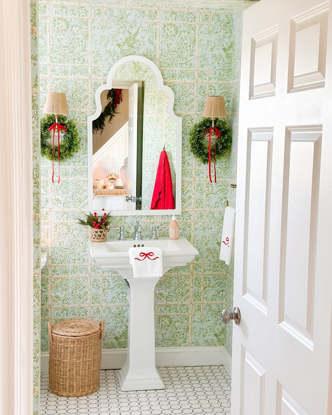 Green floral bathroom with red ribbon wreaths, bow towels, and festive Christmas accents