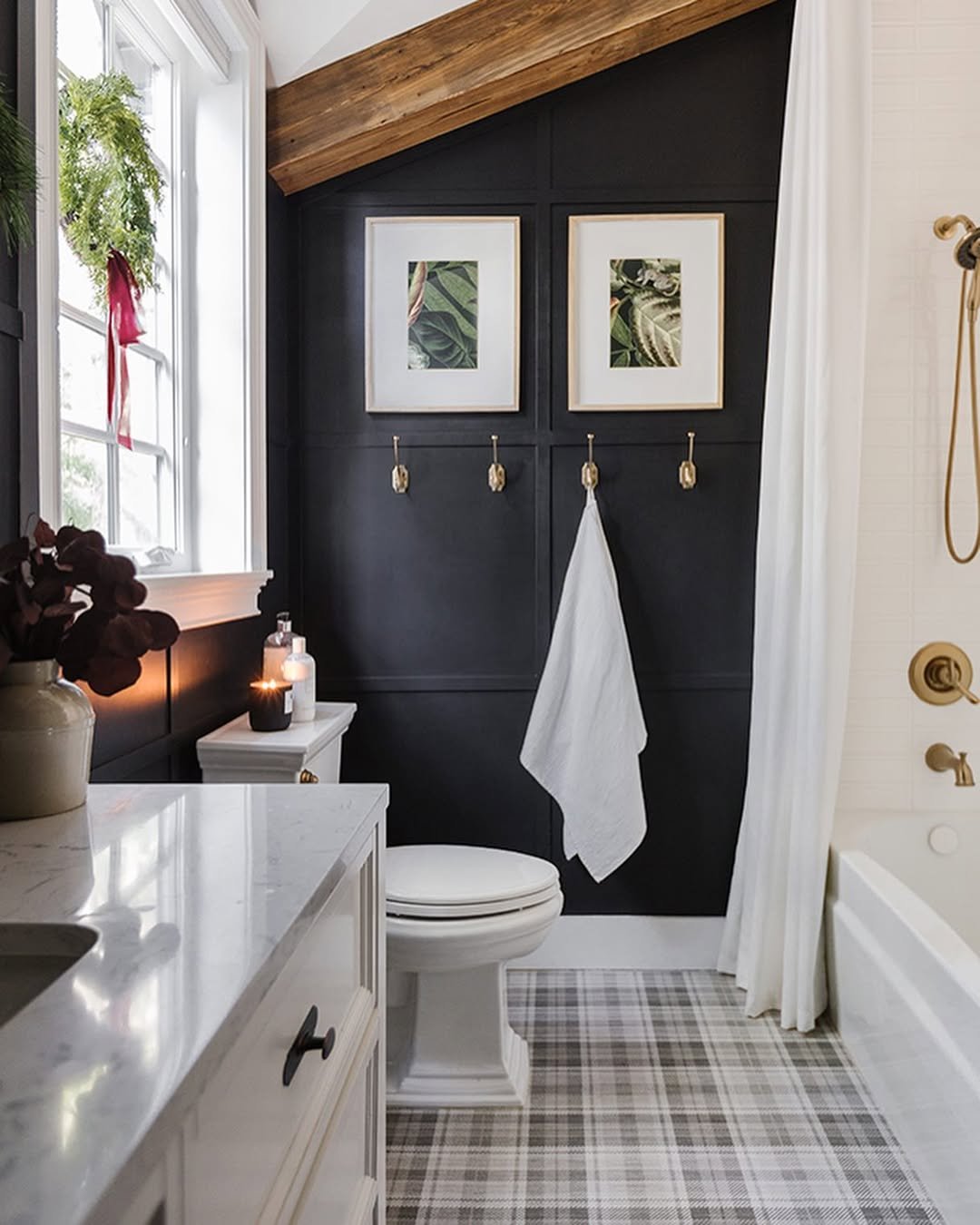 Black paneled bathroom with wreath, red ribbon, plaid rug, and winter holiday accents