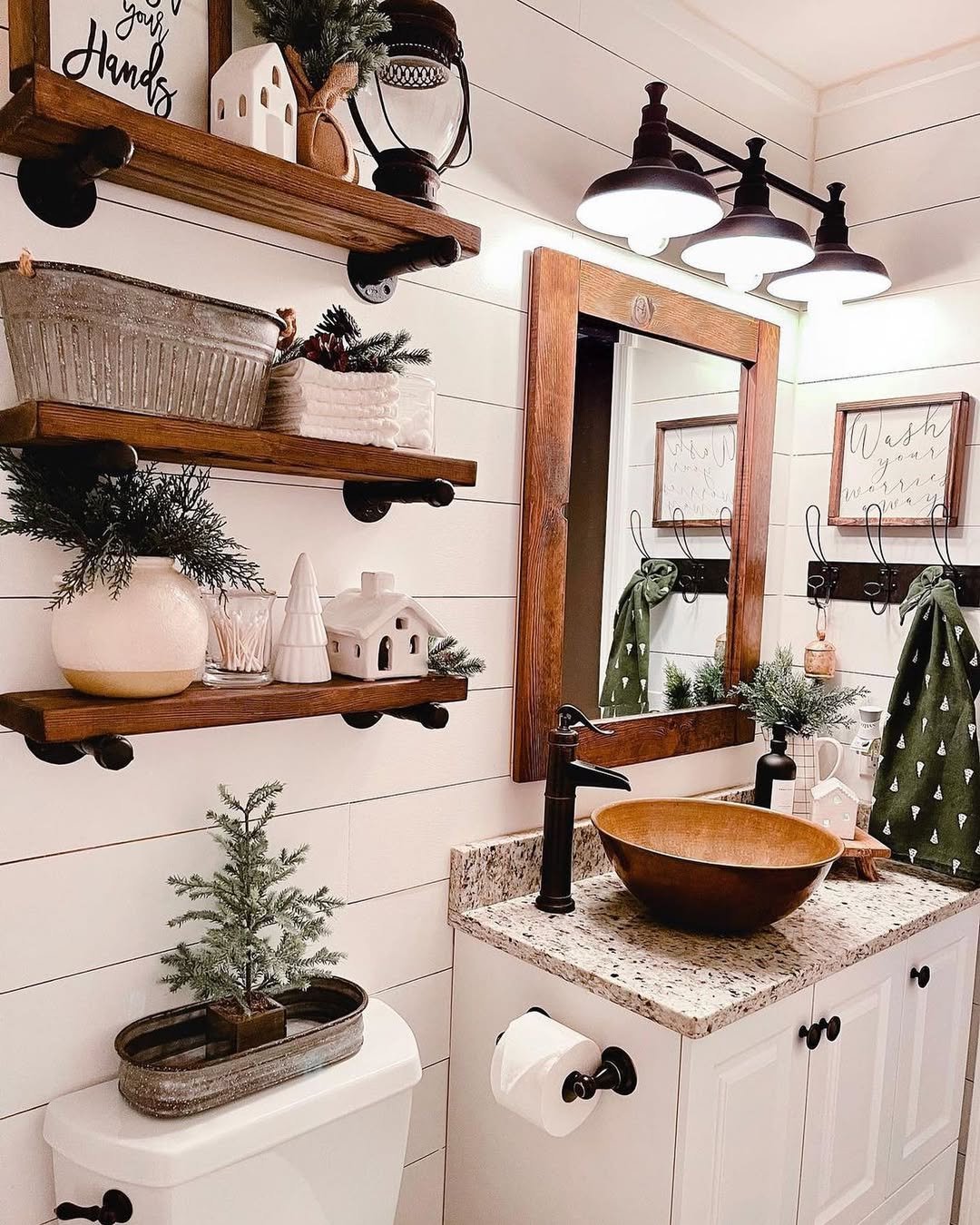 Christmas bathroom decor ideas featuring rustic shelves, evergreen accents, a wood mirror, and farmhouse bathroom styling