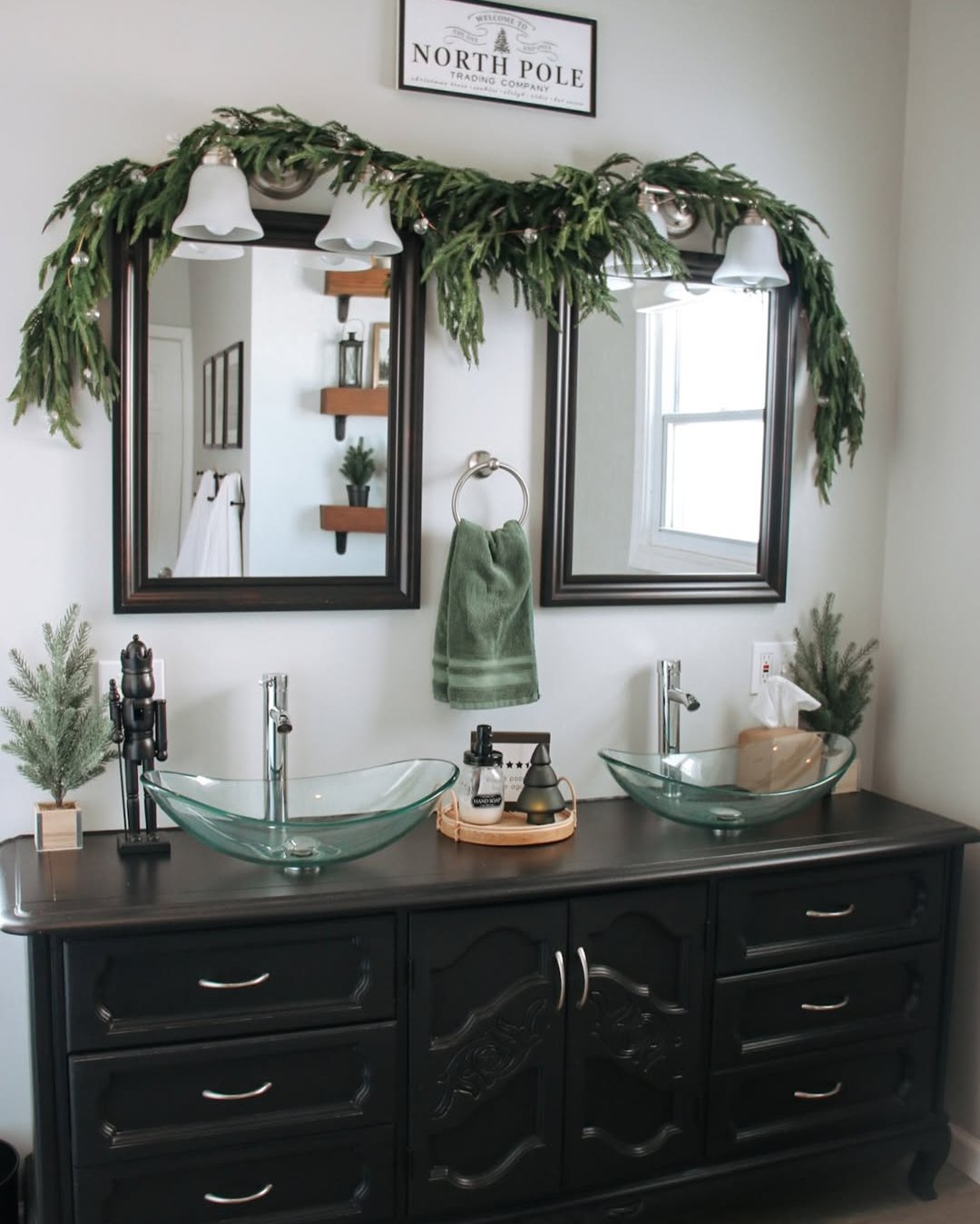Evergreen garland draped over bathroom mirrors with festive woodland accents