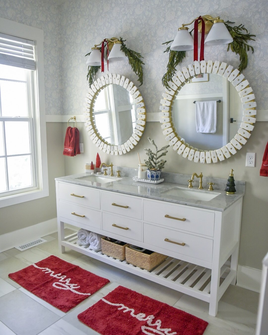 Red holiday bathroom with evergreen mirror garlands, ribbon accents, and festive bath mats