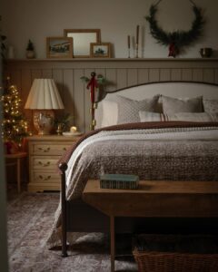 Christmas bedroom decor ideas featuring an evergreen wreath, glowing tree, layered bedding, and warm wood accents