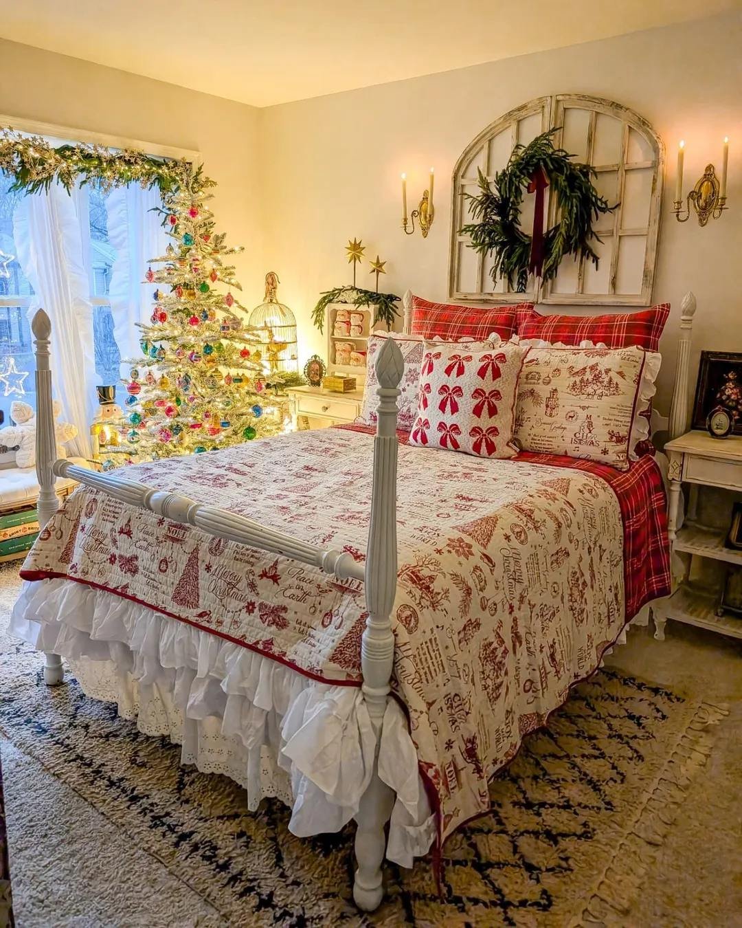 Warm Christmas bedroom with vintage quilt, plaid pillows, glowing tree, wreath, and evergreen garland