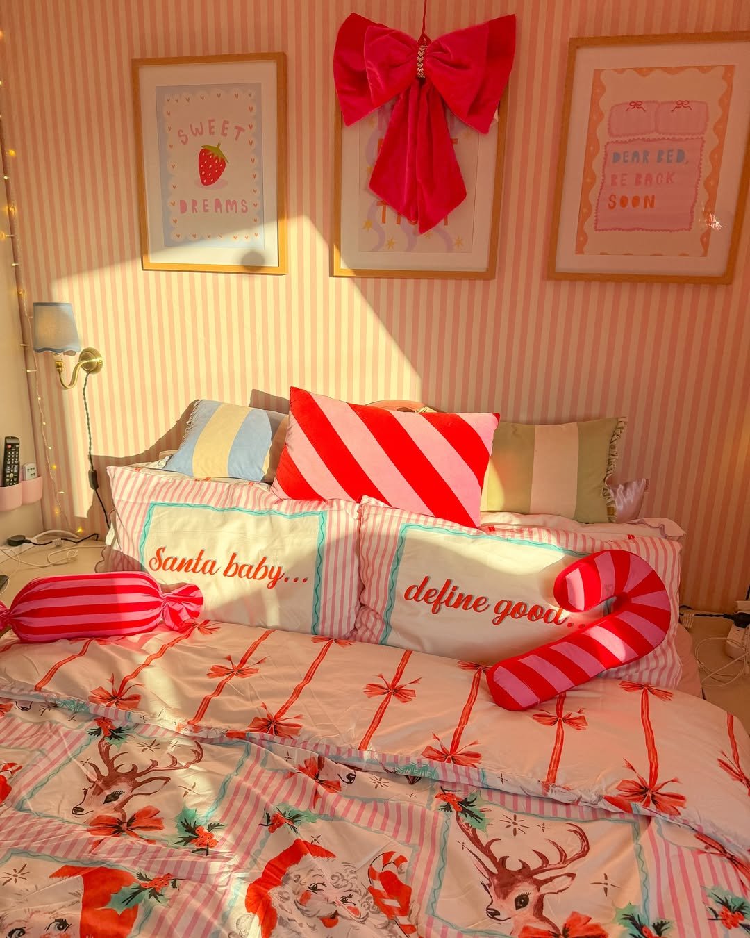 Red bow, candy-striped pillows, festive bedding, and reindeer accents create a cheerful holiday bedroom