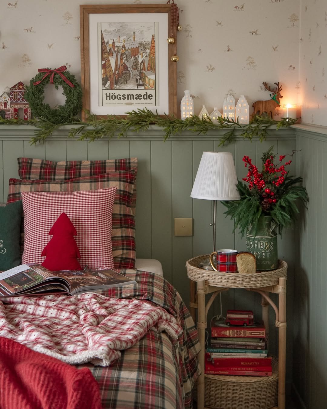 Plaid bedding, evergreen garland, glowing village houses, and festive bedroom accents