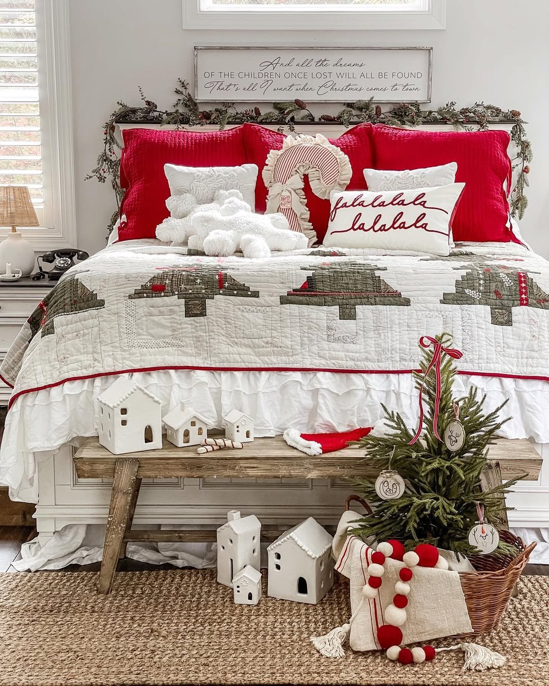Christmas bedroom decor ideas with red quilted pillows, garland, patchwork bedding, and a small decorated tree