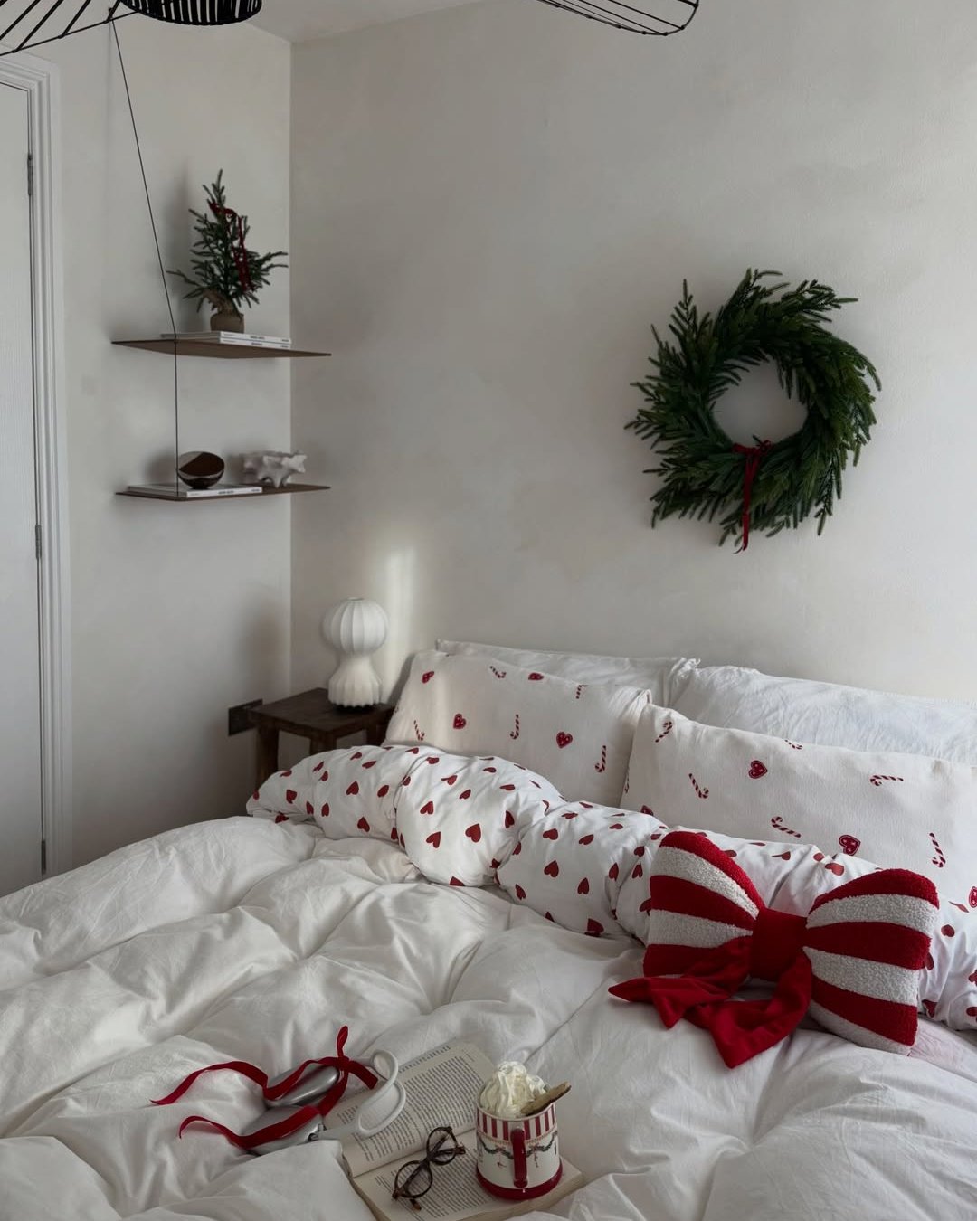 Evergreen wreath, festive red-and-white bedding, candy cane pillows, and cozy Christmas bedroom styling