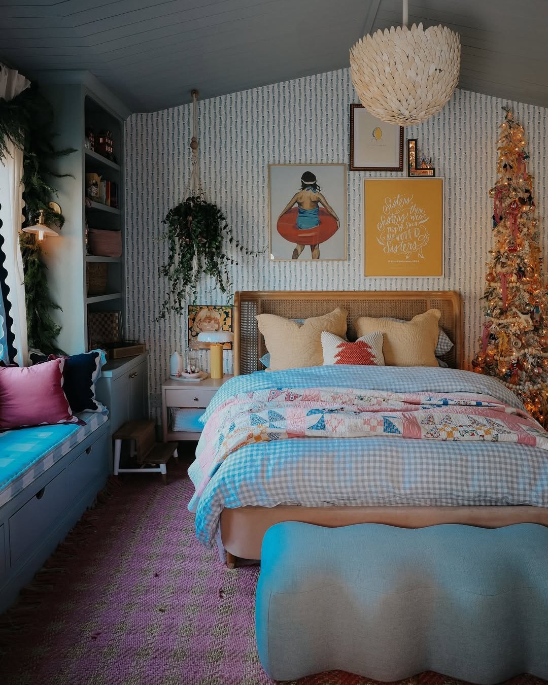 Colorful Christmas bedroom with layered quilts, a glowing decorated tree, and cozy blue furnishings