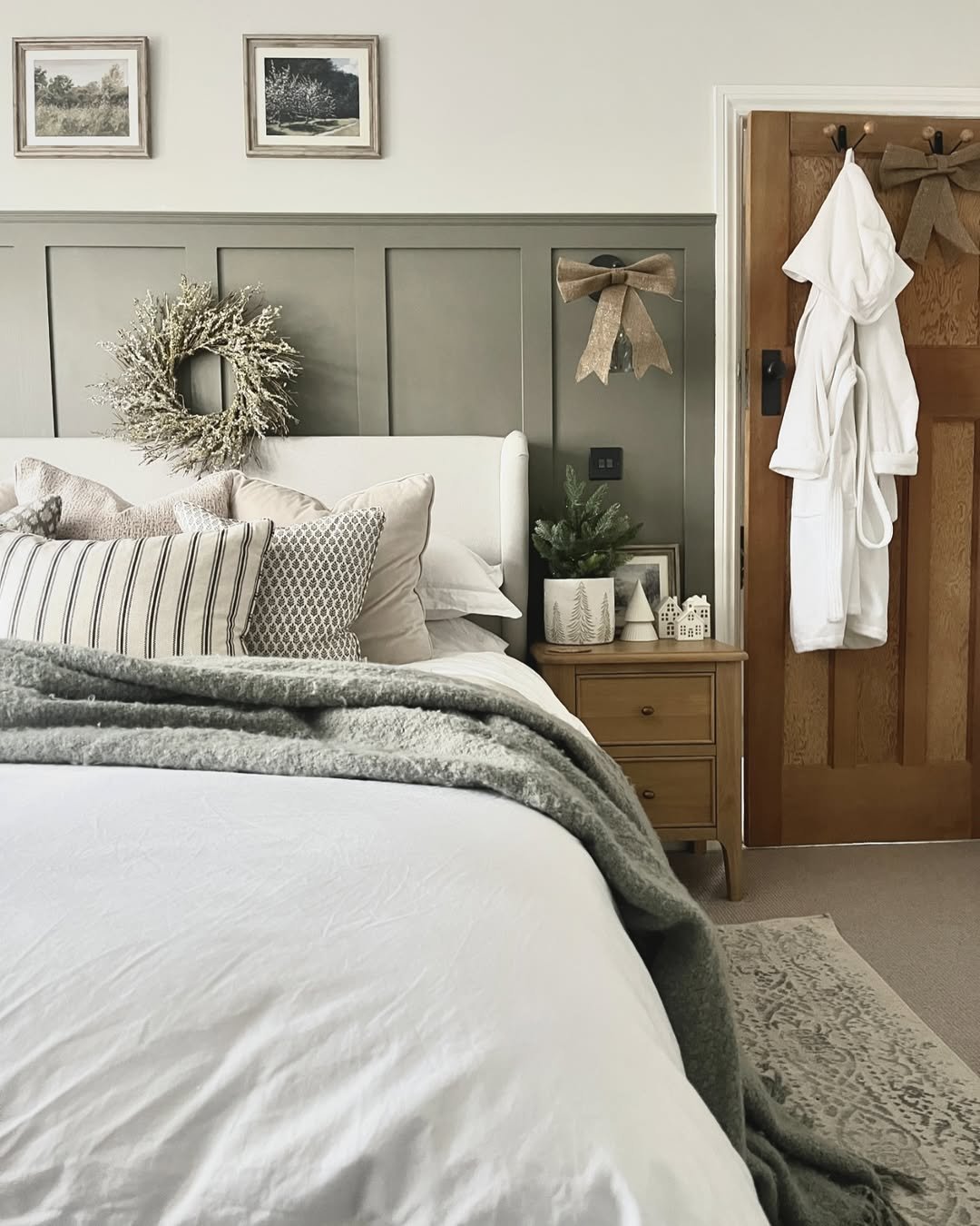 Christmas bedroom decor ideas featuring a frosted wreath, neutral bedding, bows, and a small tree