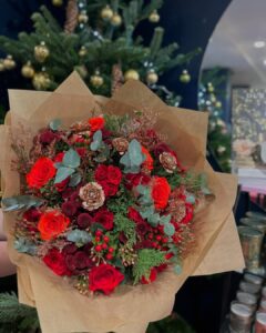 christmas floral arrangements with red roses, berries, evergreen, eucalyptus, pinecones, and kraft-paper wrapping