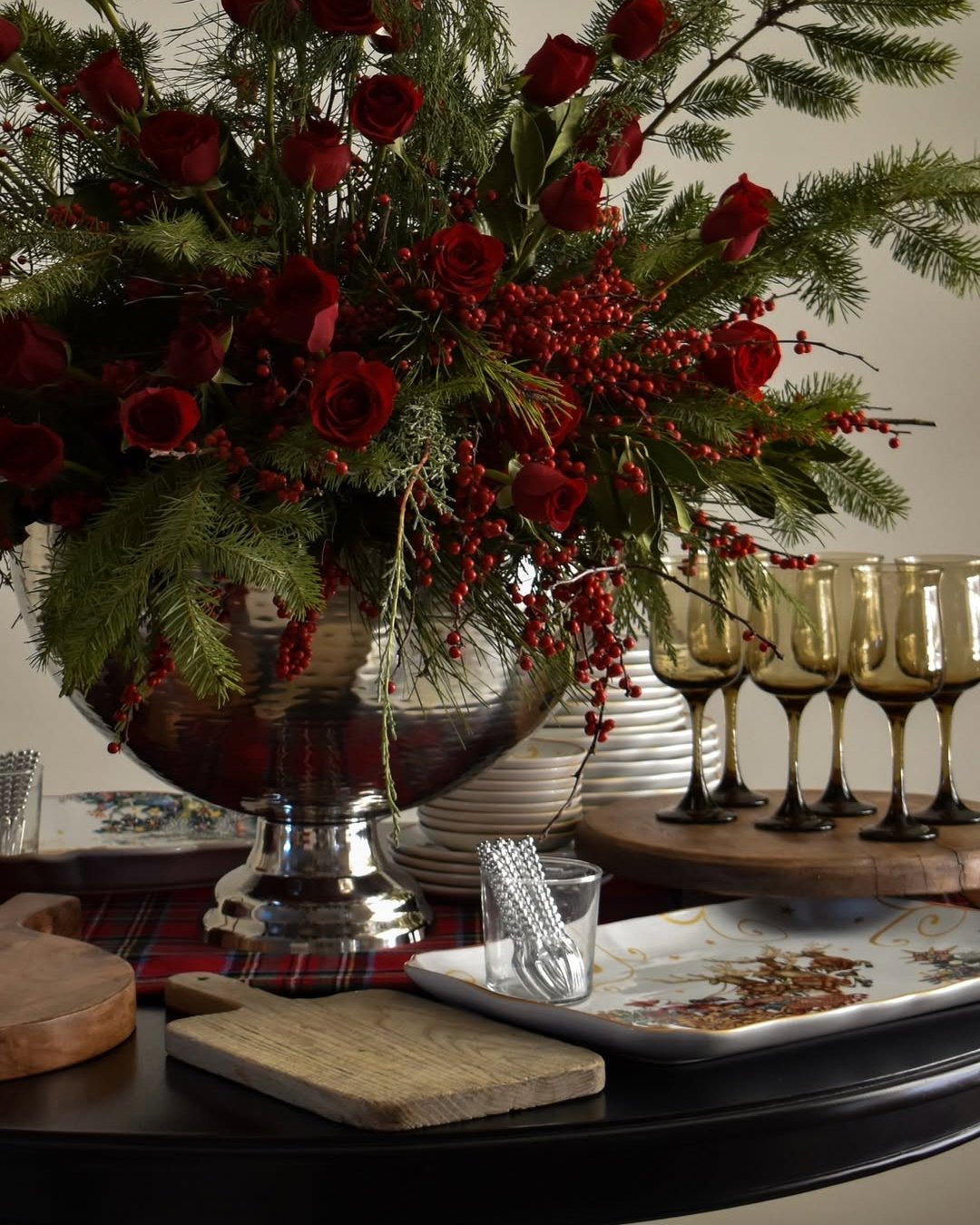 christmas floral arrangements with burgundy roses, evergreen branches, and cascading red berries in a silver bowl