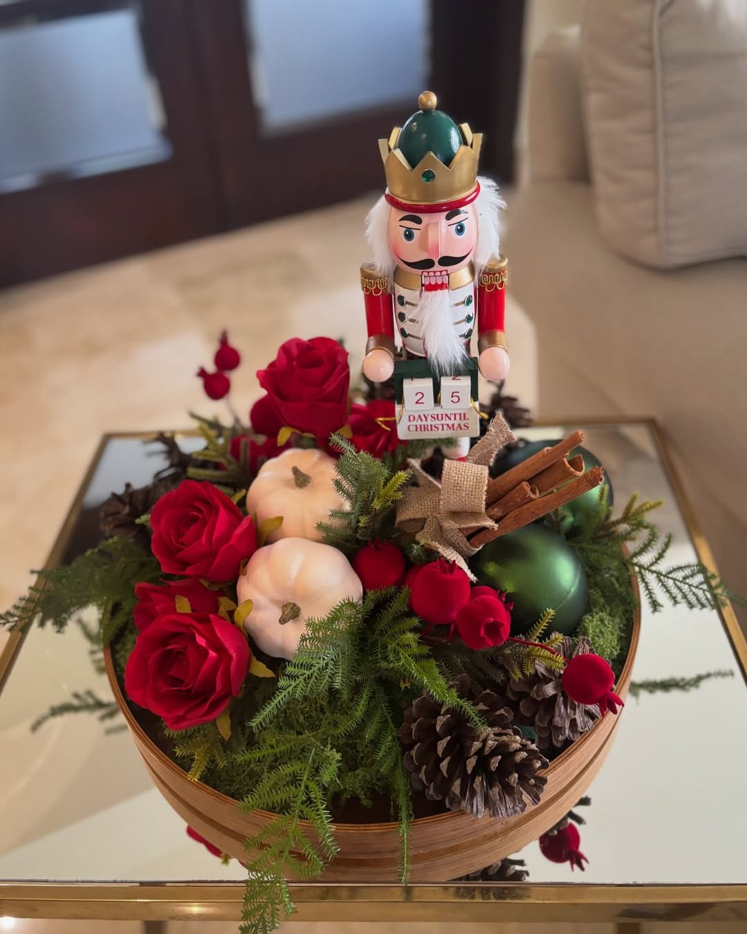 Christmas floral arrangements with red roses, evergreen branches, pinecones, ornaments, cinnamon, and a nutcracker centerpiece