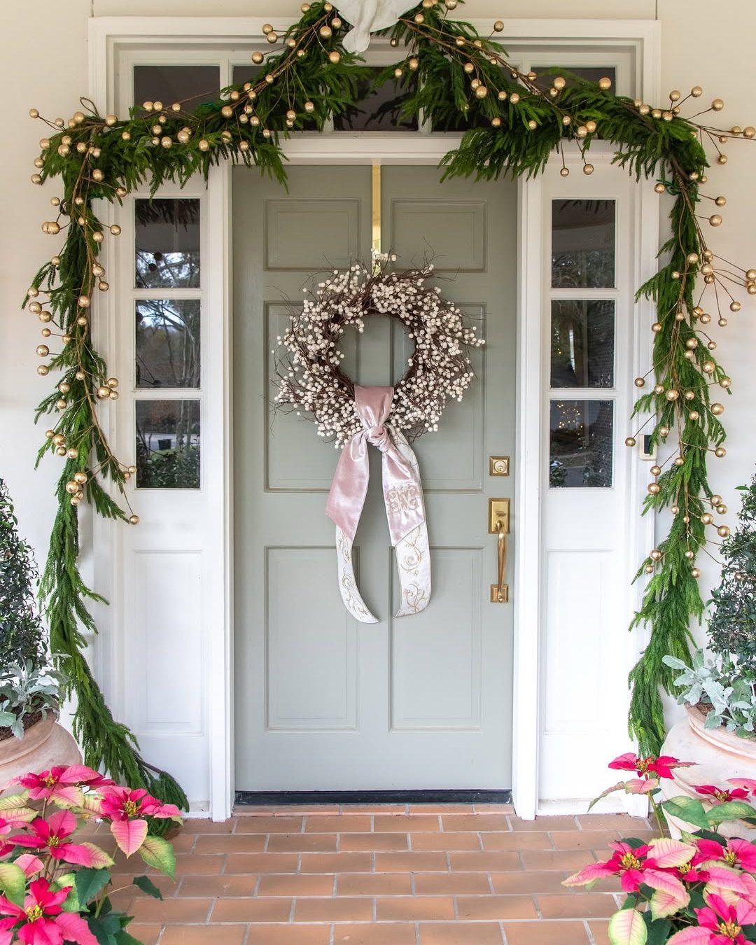 christmas front door decor ideas with golden berry garland, white berry wreath, and poinsettias