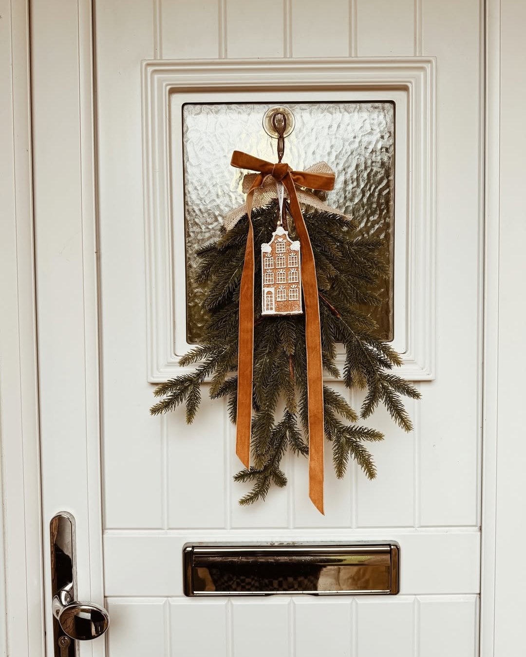 Christmas door greenery with velvet bow and gingerbread house ornament