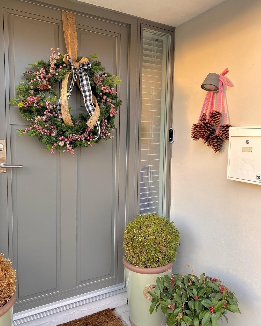 Evergreen Christmas wreath with burlap ribbon, pink berries, pinecones, and matching doorway accents