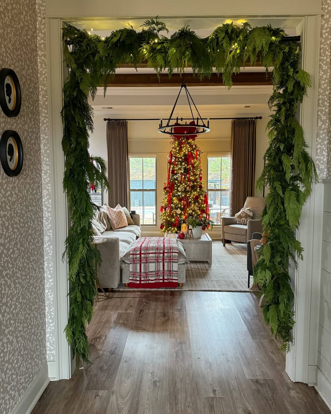 Lush evergreen doorway garland with warm lights framing a decorated Christmas living room