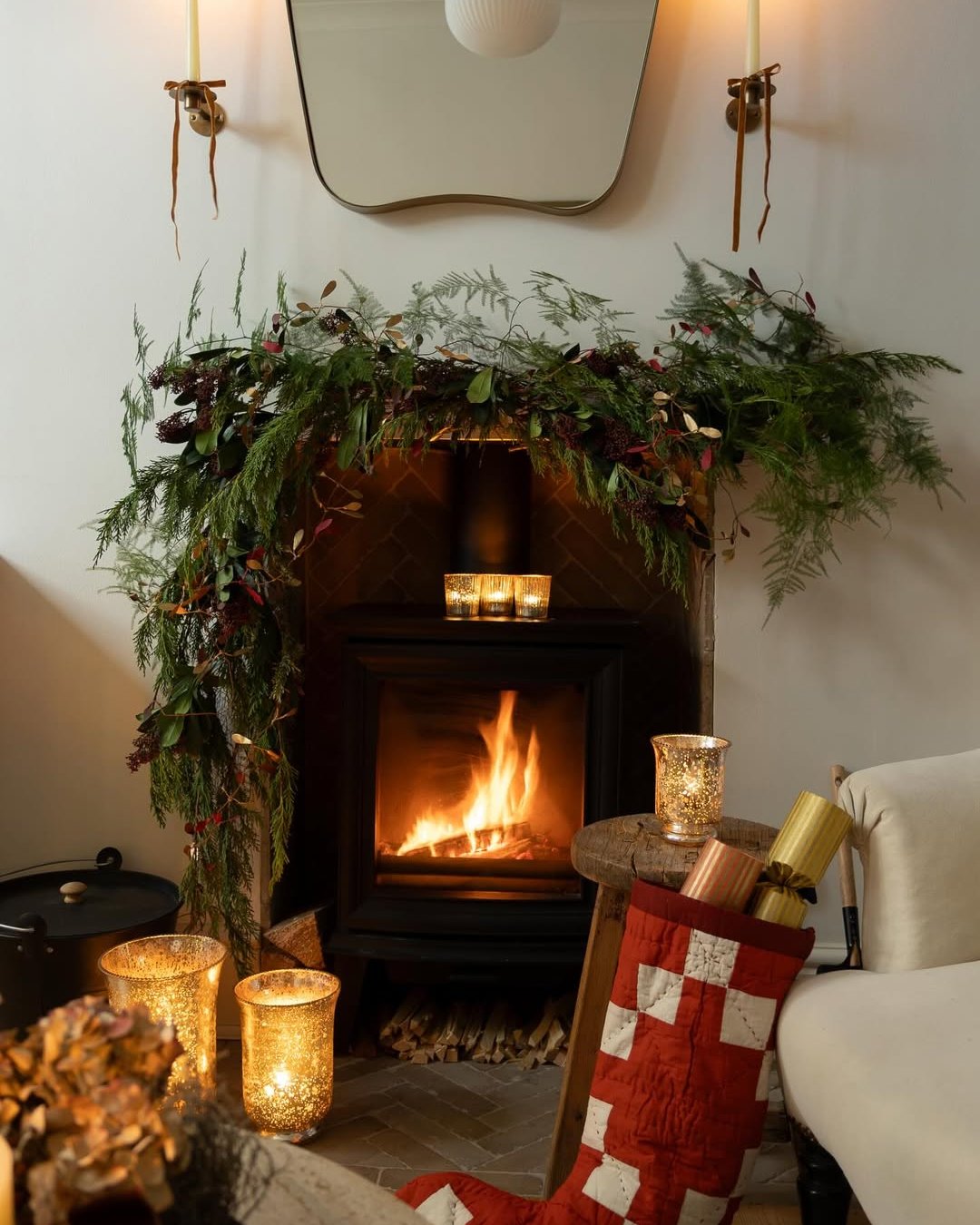 Woodland Christmas mantel garland with evergreen branches, berries, candles, and a cozy fireplace