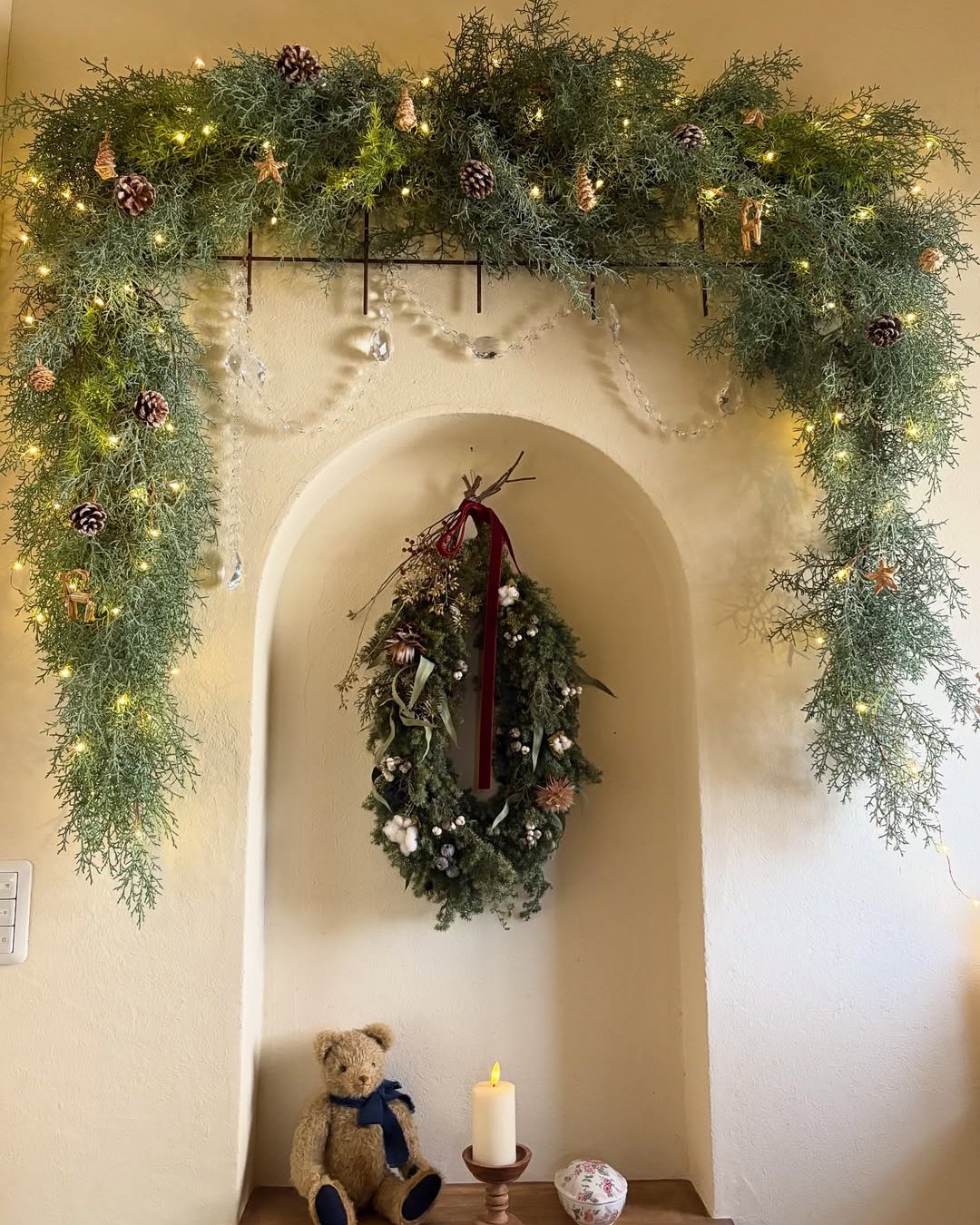 Evergreen arch garland with pinecones and glowing lights framing a cozy holiday nook