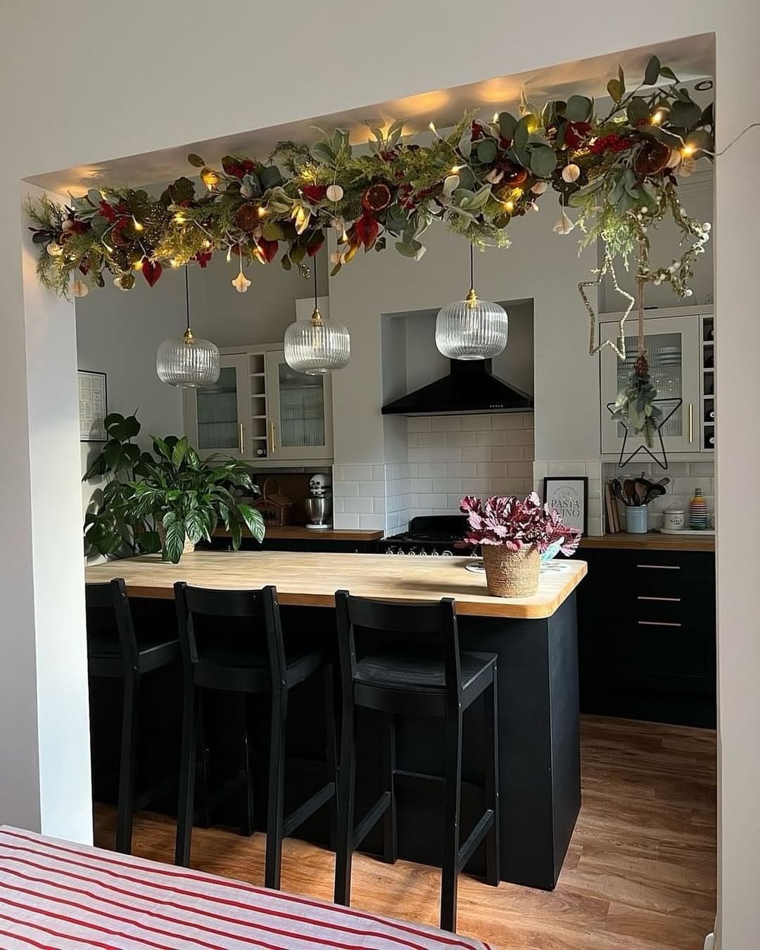 Eucalyptus kitchen garland with berries, dried citrus, ornaments, stars, and warm lights