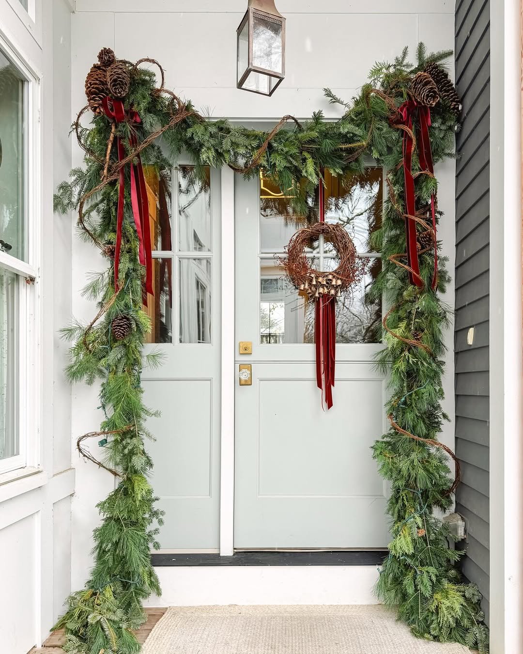 christmas garland ideas with pinecones, red ribbon, evergreen branches, and a grapevine wreath framing a doorway