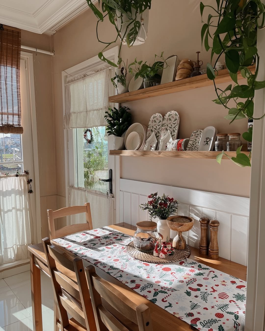 Christmas kitchen decor ideas featuring a festive botanical table runner, wooden accents, holiday dishes, plants, and Santa decorations