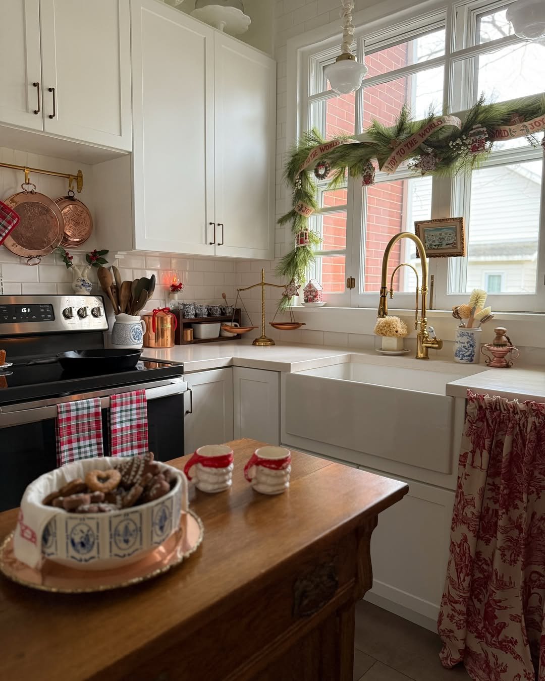 Christmas farmhouse kitchen with pine garland, vintage ribbon, plaid towels, and festive accents