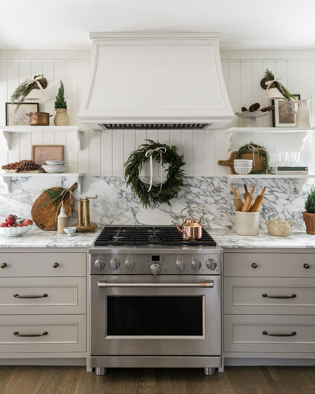 christmas kitchen decor ideas featuring an evergreen wreath, pinecones, and neutral shelf accents