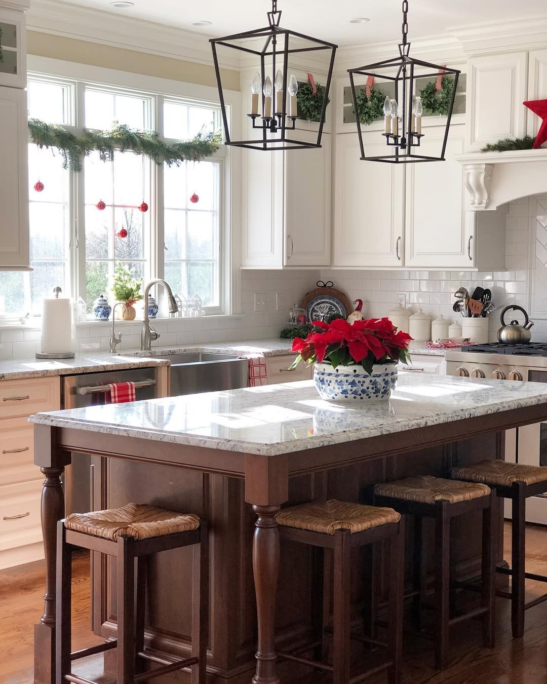 Christmas kitchen decor ideas with evergreen window garland, red ornaments, poinsettias, wreaths, and festive kitchen accents