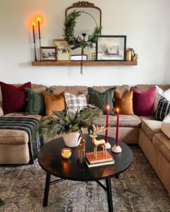 christmas living room decor ideas with evergreen mirror garland, red candles, vintage art, and warm neutral seating