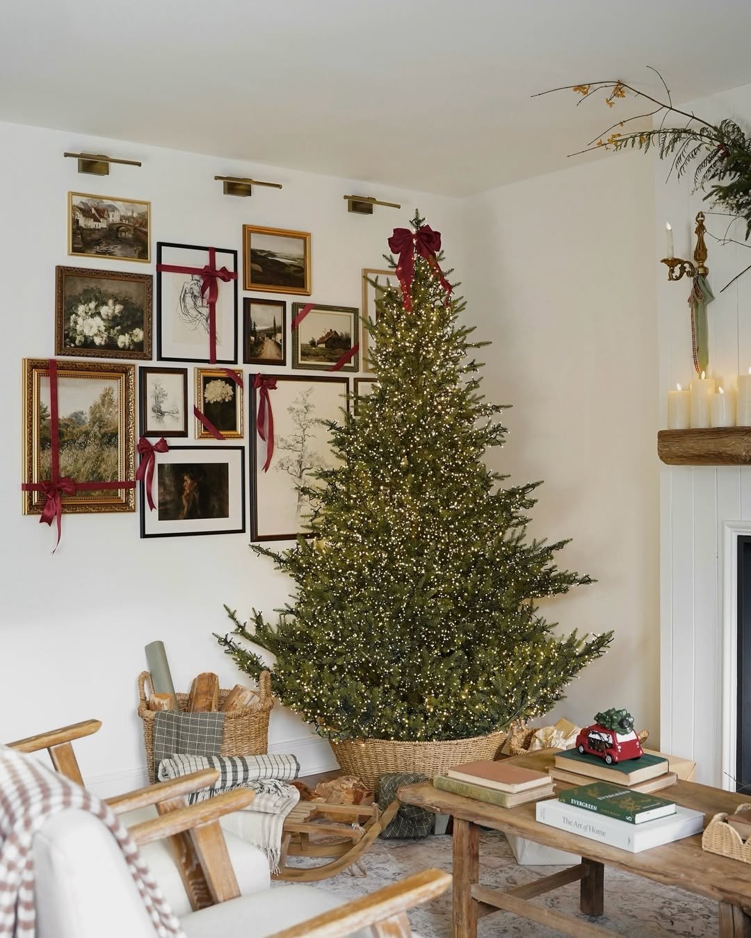 Warm Christmas living room with illuminated tree, red velvet bows, vintage gallery wall, wicker basket, and wooden coffee table