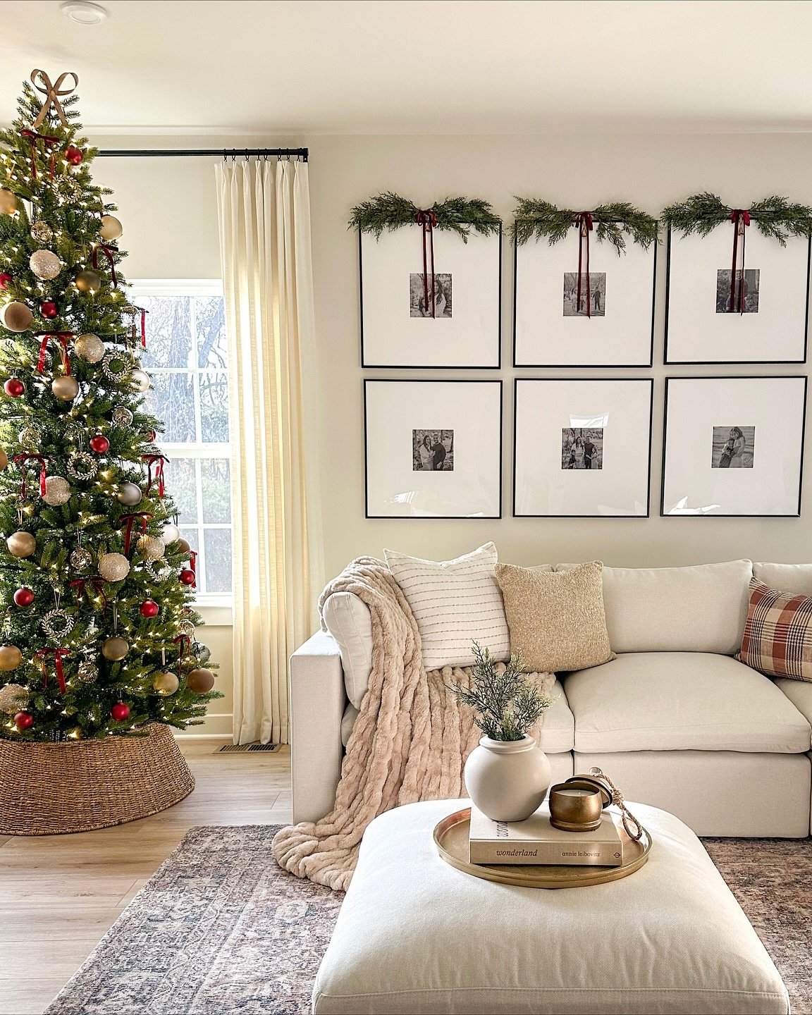 Neutral Christmas lounge with ribboned tree, greenery-topped gallery wall, and cozy textured seating