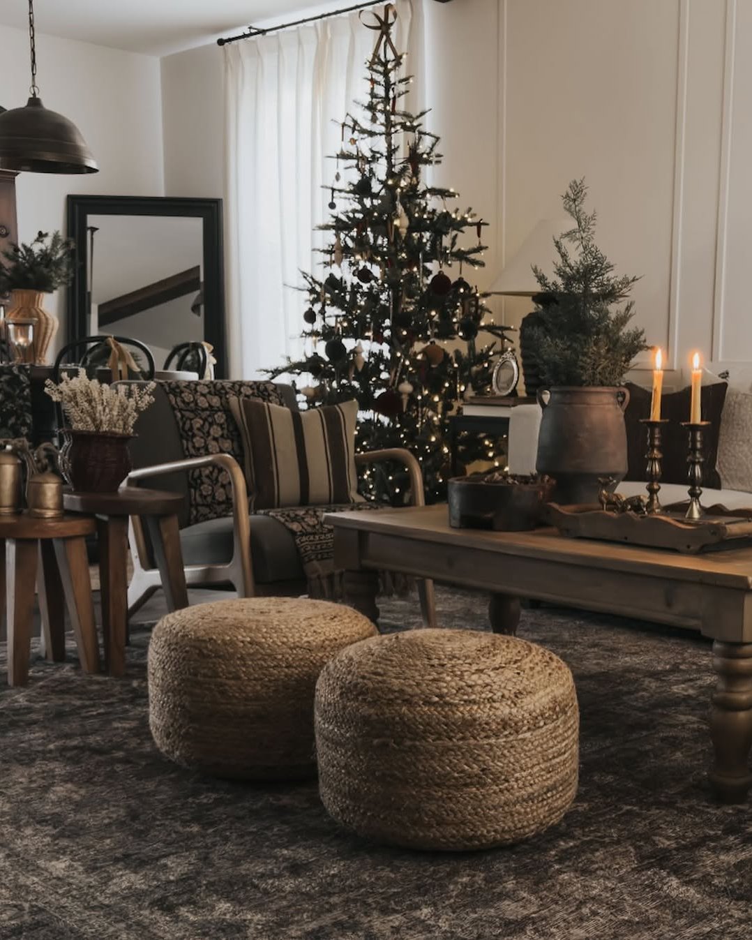 Christmas living room decor ideas with a rustic tree, woven ottomans, candles, and natural neutral accents