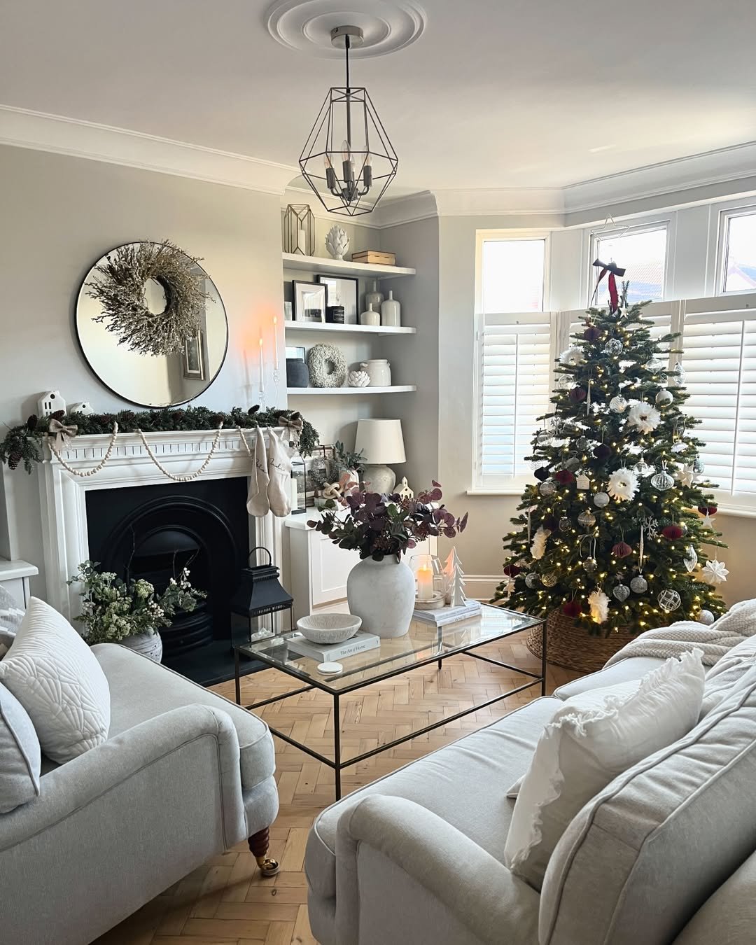 Neutral Christmas tree with berry ornaments, ivory flowers, glowing lights, and a layered mantel
