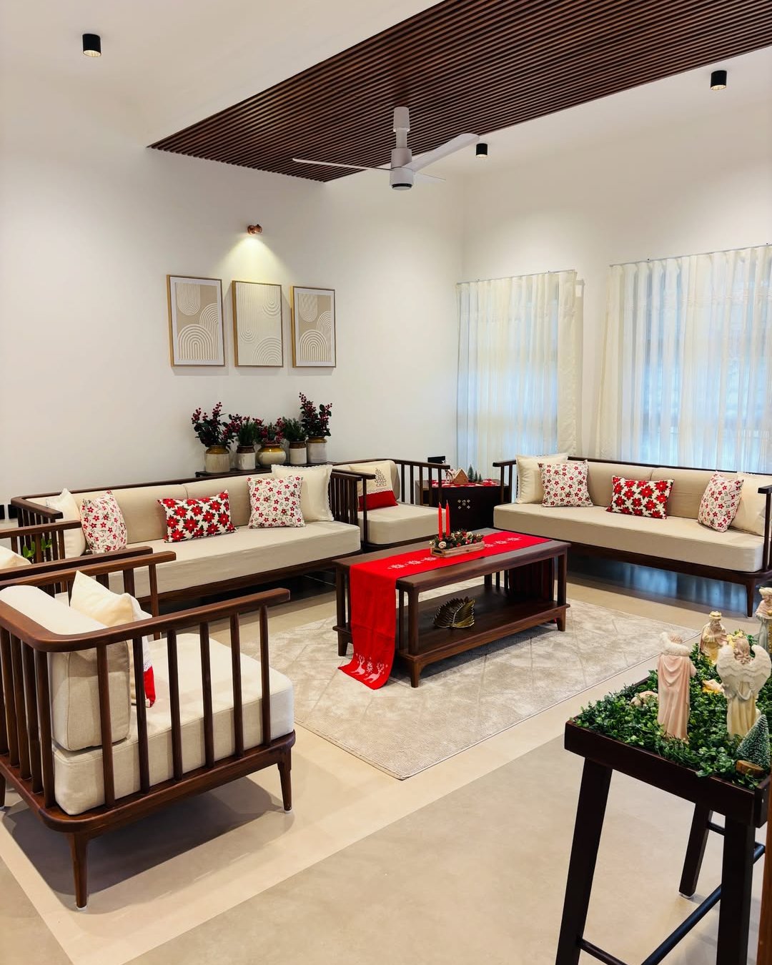 Festive living room with red accents, patterned pillows, greenery, candles, and wooden furniture