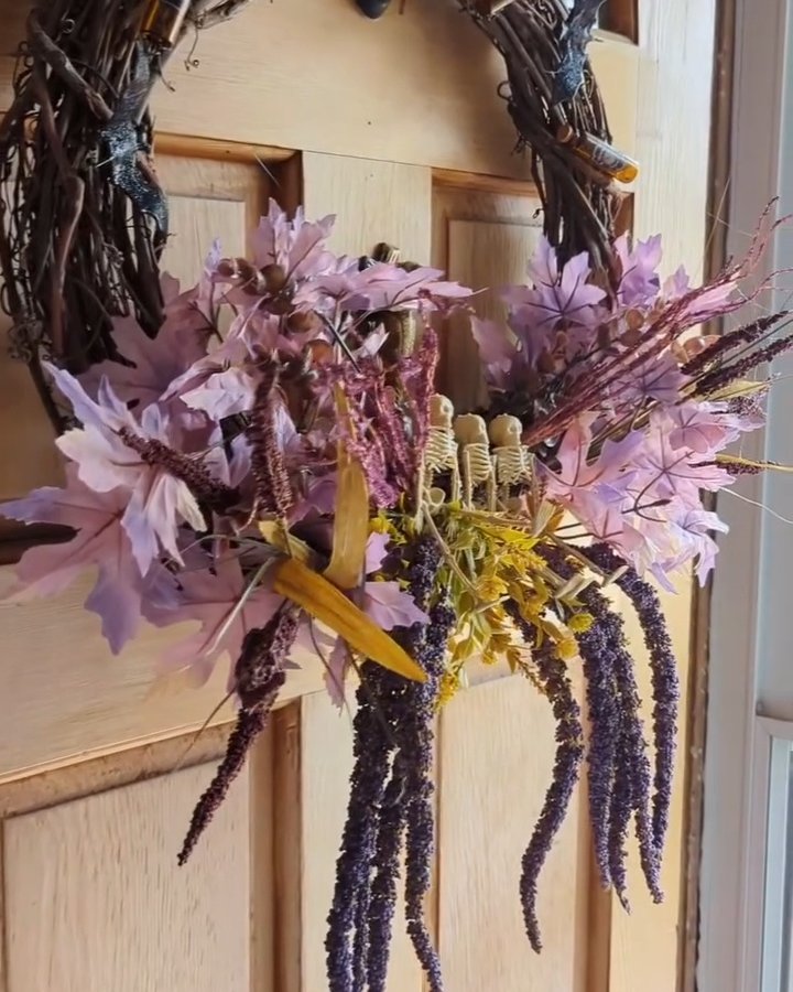 Cascading purple flowers and skeleton accents on a handmade Halloween door wreath