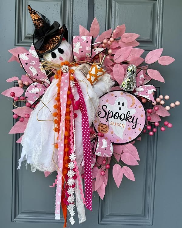 Pink foliage and playful ghost ribbons frame a witch hat diy halloween wreath with a spooky season sign.