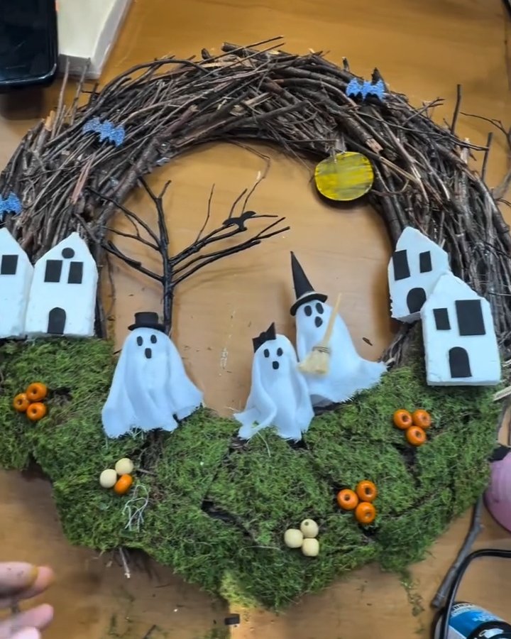 Mossy haunted village wreath with ghosts, twig branches, paper houses, bats, and colorful Halloween accents