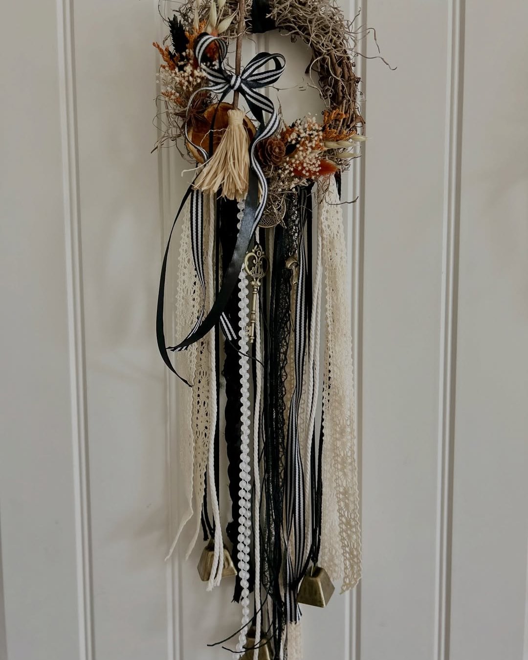 Bohemian Halloween door wreath with black lace, striped ribbon, dried florals, tassels, and trailing textures