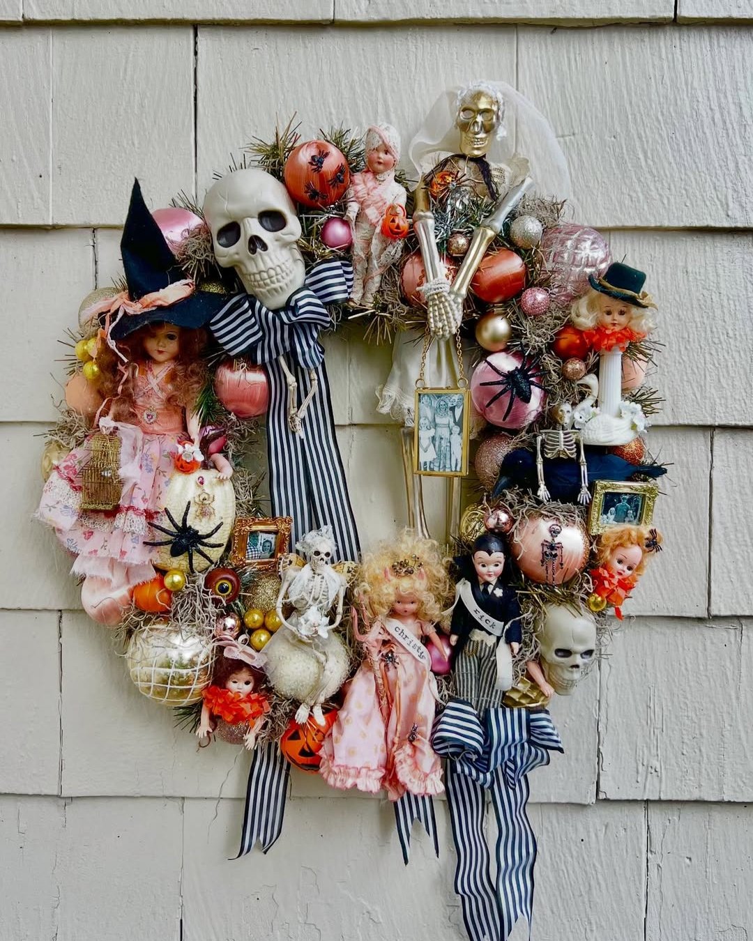 Vintage Halloween door wreath with dolls, skeletons, pumpkins, ornaments, moss, and striped ribbon