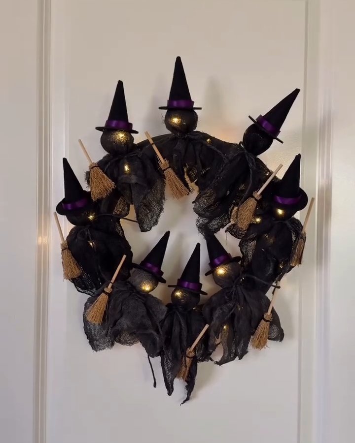 Handmade Halloween witch wreath with glowing black figures, purple hats, and tiny broomsticks